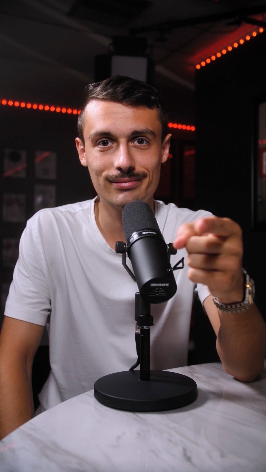 Jason Wojo seated at a microphone in a studio, pointing towards the camera
